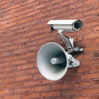 Lautsprecher und Kamerainstallation seitlich an einer rötlichen Backsteinwand installiert.