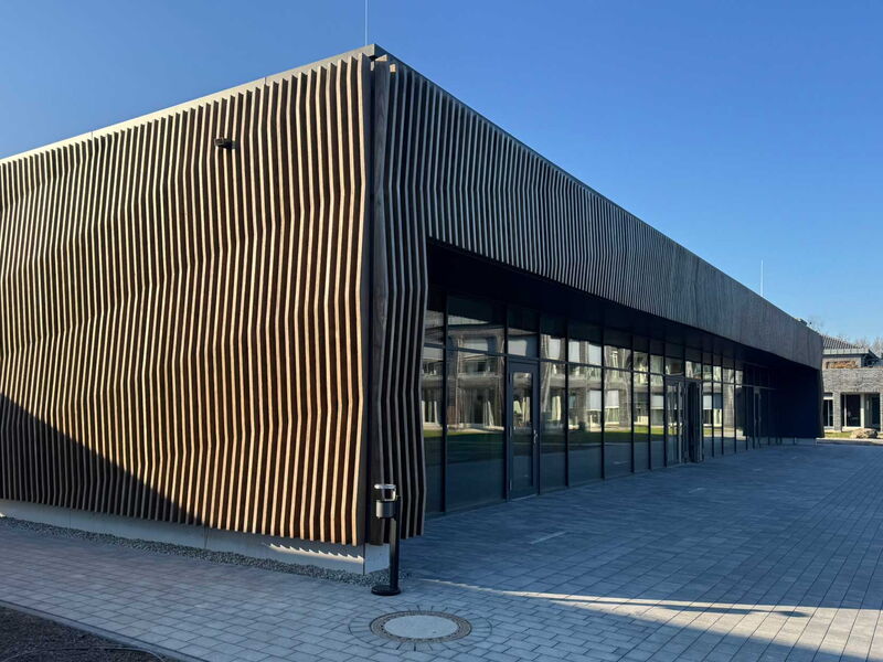 Aussenfassade eines Schulungszentrums mit großer Glasfassade und gepflastertem Vorplatz.