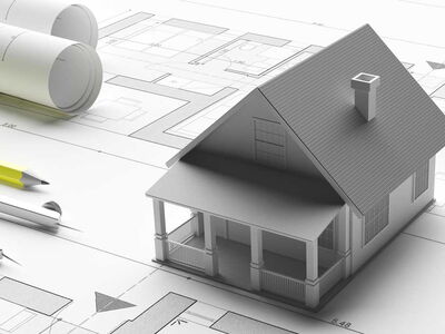 3D Haus steht auf Bauplänen, links liegt ein Zirkel und ein Bleistift.